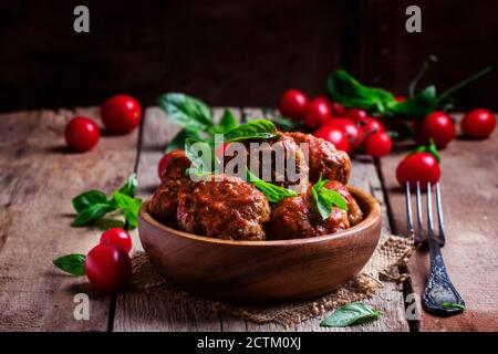 Polpette di maiale e manzo con salsa piccante di pomodoro in ciotola, fondo ligneo vintage, fuoco selettivo Foto Stock