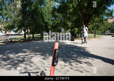 Tampere, Finlandia - 26 LUGLIO 2019. Un uomo da solo che guida uno scooter elettrico in un parco pubblico in una giornata estiva soleggiata. Foto Stock