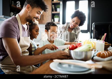 Felice famiglia americana africana la preparazione di un alimento sano insieme in cucina Foto Stock