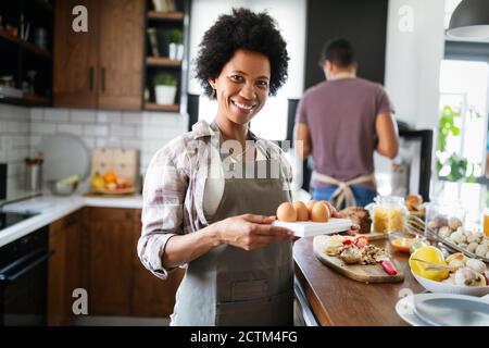 Felice coppia nera cucina e degustazione di cibo sano in cucina Foto Stock