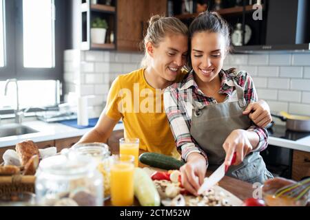Felice giovane coppia divertirsi in cucina moderna durante la preparazione cibo fresco Foto Stock