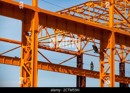 Kostanay/Kazakhstan - Maggio 14 2012: Costruzione di una nuova fabbrica. Assemblaggio di una struttura in acciaio arancione. Lavoratore ad alta quota (industriale Foto Stock