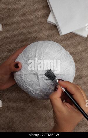 Fare artigianato fatto in casa - zucca per Halloween da papier-mache, bastone pezzi di tovaglioli con una spazzola, fai da te Foto Stock