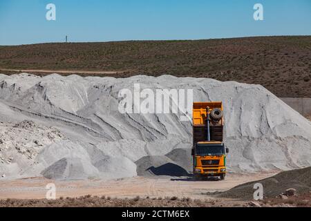 Mynaral/Kazakhstan - Aprile 23 2012: Stoccaggio di materie prime nell'impianto di cemento Jambyl. Cumulo di minerali clinker e dumper giallo. Foto Stock