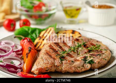 Primo piano di bistecca alla griglia con erbe, spezie e verdure sul piatto. Concetto di cucina italiana. Foto Stock
