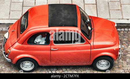 Red Fiat 500 parcheggiata su una strada acciottolata italiana. Auto d'epoca italiana. Foto Stock