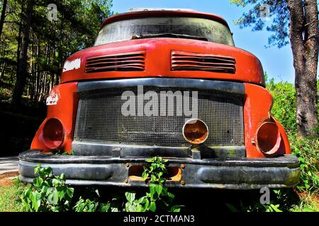 Vista frontale di un vecchio camion rosso con fari mancanti, abbandonato nei boschi vicino ad una strada a Sagada, provincia di montagna, Filippine Foto Stock