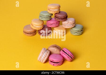 Dolci, dessert e dolci. Primi piano di macaroon francesi originali multicolore sono bellissimi arrangiati su sfondo giallo. Festa, compleanno Foto Stock