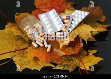 Pillole su foglie di acero giallo e rosso, flacone di capsule e blister confezione di compresse. Concetto di farmacia, antidepressivi, vitamine per l'immunità Foto Stock