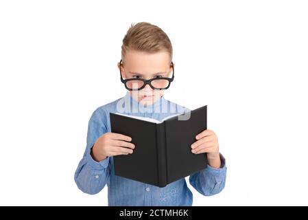 Carino studente serio legge libro e indossare occhiali mentre in piedi in studio, isolato su bianco Foto Stock