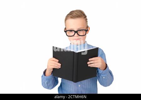 Carino studente serio legge libro e indossare occhiali mentre in piedi in studio, isolato su bianco Foto Stock