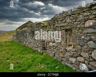 Con minacciosi cieli grigi, un abbandonato, derelict croft / fattoria isola di yell in Shetland, Scozia, Regno Unito Foto Stock