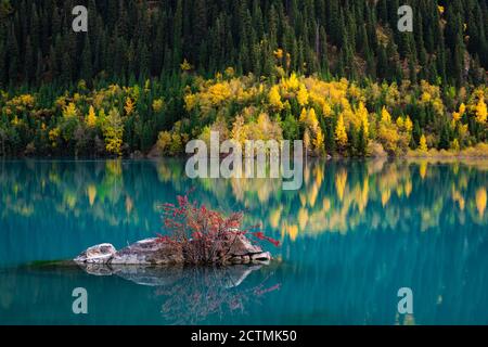 Lago di montagna Issyk. Umore autunnale. Gli alberi ingialliti si riflettono nell'acqua turchese Foto Stock