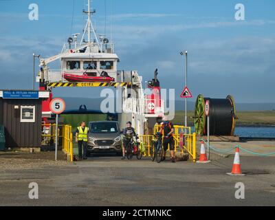 I ciclisti lasciano il traghetto per auto roro MV Geira, situato tra le isole, al terminal dei traghetti di Belmont, sull'isola di Unst a Shetland, Regno Unito Foto Stock