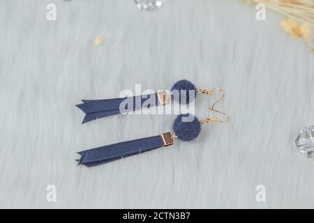 Orecchini blu fatti a mano. Abbinato al bouquet giallo secco. Metterlo sulla coperta bianca di lana. Ha un aspetto molto elegante ed elegante. Foto Stock