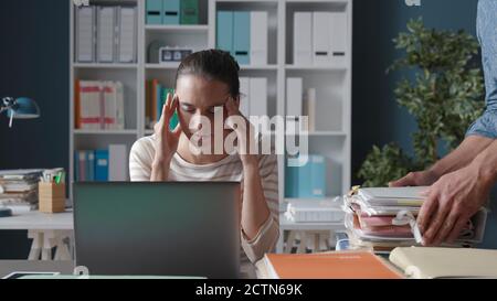 Stressata giovane donna che lavora in ufficio, è stanca e ha un mal di testa Foto Stock