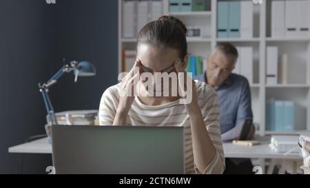 Stressata giovane donna che lavora in ufficio, è stanca e ha un mal di testa Foto Stock