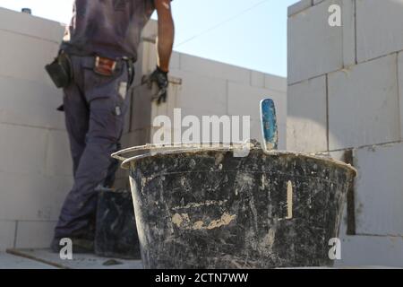 Il lavoratore di costruzione (muratore) lavora sul cantiere Foto Stock