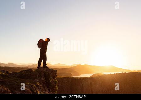 Imprenditore maschile asiatico in tuta formale mostrando movimento di breakdance e. equilibrio sul braccio in tribuna sulla strada della città mentre si guarda alla telecamera Foto Stock