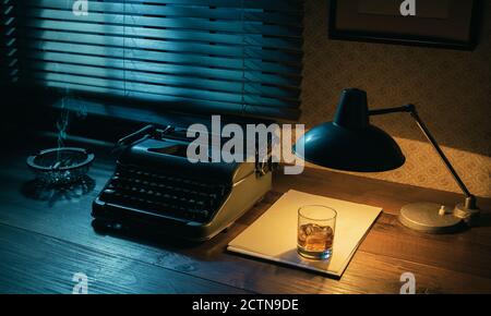 Desktop di scrittore in stile noir con macchina da scrivere e un bicchiere di whisky, creatività e ispirazione Foto Stock