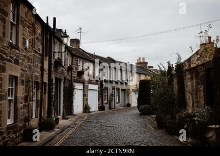 Vista prospettica della vecchia strada stretta con grunge edifici residenziali Sullo sfondo del cielo grigio nelle Highlands scozzesi Foto Stock