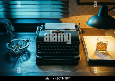 Desktop di scrittore in stile noir con macchina da scrivere e un bicchiere di whisky, creatività e ispirazione Foto Stock