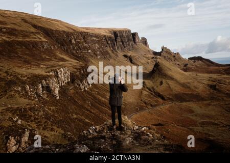 anonimo turista maschile con fotocamera professionale che scatta foto di Montagne meravigliose nelle Highlands scozzesi in autunno Foto Stock