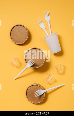 Alto angolo di contenitori in cartone con forcelle e cucchiai in plastica sono dotati di piccoli bicchieri in plastica per il servizio di ristorazione da asporto tavola arancione Foto Stock