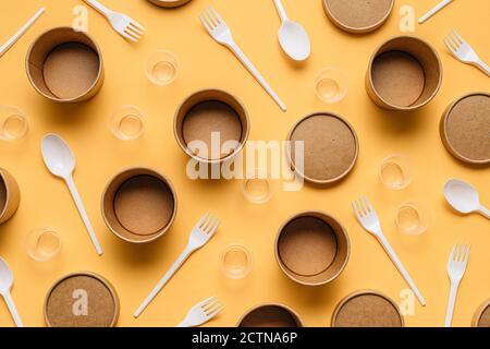 Alto angolo di contenitori in cartone con forcelle e cucchiai in plastica sono dotati di piccoli bicchieri in plastica per il servizio di ristorazione da asporto tavola arancione Foto Stock