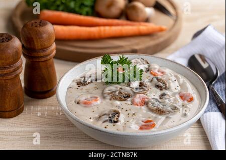 Ciotola di crema di zuppa di funghi su rustico tavolo di legno con ingredienti in background Foto Stock