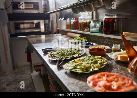 Vista dall'alto di vari ingredienti freschi per la preparazione della pizza tavolo in marmo nella cucina del ristorante Foto Stock