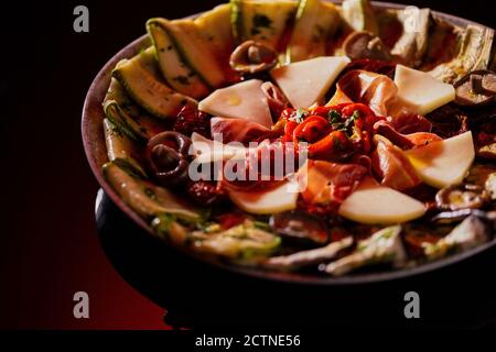 Appetitosa pizza aromatica sottile con zucchine grigliate e melanzane con pomodori e funghi serviti in ciotola su fondo scuro Foto Stock