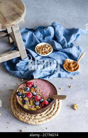 Un angolo di donna irriconoscibile con gustosa colazione e gustosa recipiente per frullati con yogurt e frutti di bosco Foto Stock