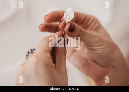 anonimo artigianale femminile che crea petalo di fiore da morbido plymer argilla in uno studio luminoso mentre si utilizza un attrezzo speciale Foto Stock