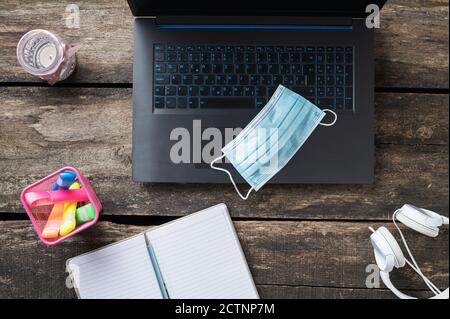 Home studiare durante il covid 19 pandemia immagine concettuale - vista dall'alto della maschera medica protettiva su computer portatile con blocco note, marcatore colorato e hea Foto Stock