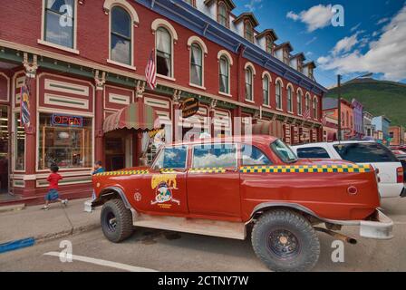 Checker Taxicab, che serve come pubblicità per il locale Grumpy's Restaurant di fronte al Grand Imperial Hotel in Greene Street, Silverton, Colorado, USA Foto Stock