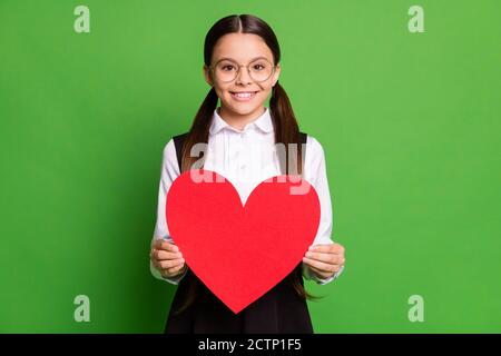 Foto di carina piccola signora scolaretta di fronte blackboard tenere carta rosso cuore figura toothy beaming sorriso febbraio maglietta bianca per le feste Foto Stock