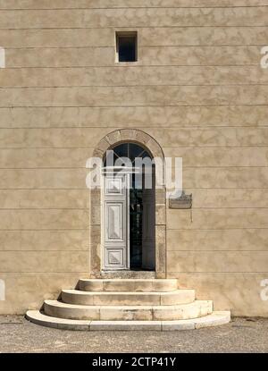 Una vecchia porta con finestra ad arco direttamente sopra; a Port Vendres, Francia. La porta è posta in una parete di stucco marrone. Foto Stock