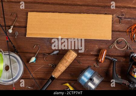 Diverse tegole da pesca con esche e bobine su sfondo marrone di legno con posto per il testo. Design per la pubblicità e la pubblicazione. Foto Stock