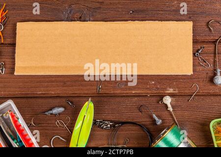 Diverse tegole da pesca con esche e bobine su sfondo marrone di legno con posto per il testo. Design per la pubblicità e la pubblicazione. Foto Stock