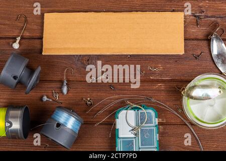 Diverse tegole da pesca con esche e bobine su sfondo marrone di legno con posto per il testo. Design per la pubblicità e la pubblicazione. Foto Stock