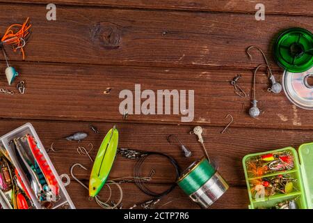 Diverse tegole da pesca con esche e bobine su sfondo marrone di legno con posto per il testo. Design per la pubblicità e la pubblicazione. Foto Stock