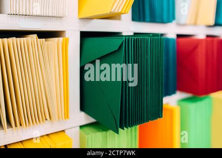 Varie buste di smistamento disposte su uno scaffale in base al colore e alle categorie di tipo. Foto Stock