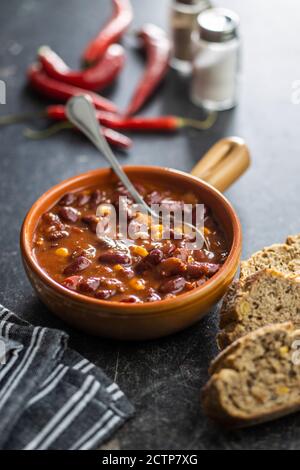 Chili con carne. Cibo messicano con fagioli in pentola e pane su tavola nera. Foto Stock