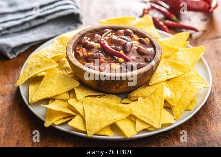 Chili con carne e tortilla chip su piatto. Cibo messicano con fagioli in ciotola di legno. Foto Stock