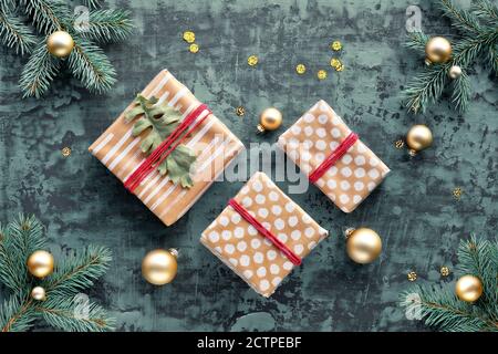 Scatole regalo di ramoscelli dell'albero di Natale avvolte in carta artigianale riciclata su sfondo turchese scuro. Foto Stock