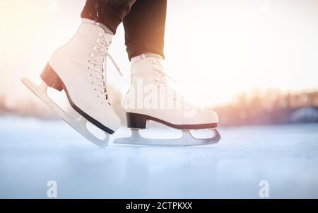La figura bianca pattina sulla pista di ghiaccio invernale con bokeh sfocato sfondo Foto Stock