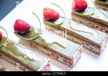 Primo piano di dessert al cioccolato al pistacchio con fragole e noci, con tavolo da pranzo Foto Stock