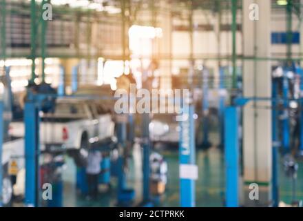 Sfondo offuscato del tecnico che ripara l'automobile in garage,meccanica che fissa in un'officina sospensione dettaglio dell'automobile sollevata alla stazione di servizio, Foto Stock