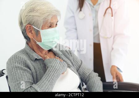 Anziani salute controllare in su, indossano maschera chirurgica Foto Stock